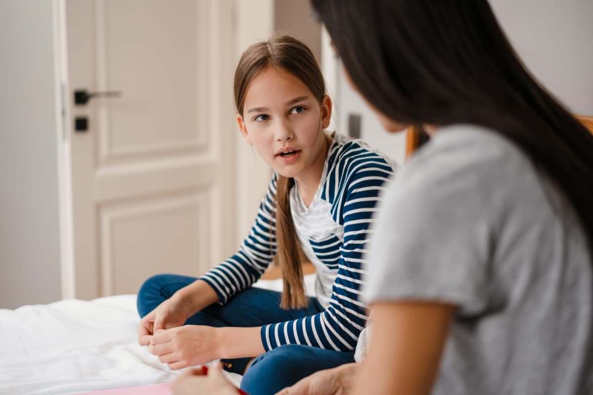 Caregiver and child having a calm talk together on a bed